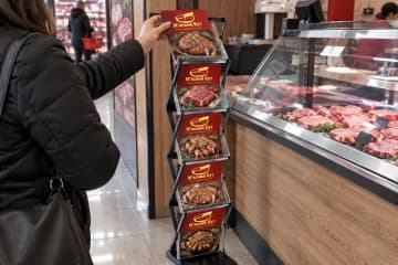 Буклетниця-конструктор у м'ясній крамниці, покупниця бере буклет