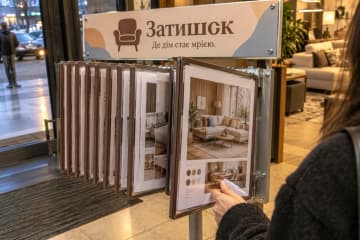 Відвідувачка гортає перекидну систему з фото меблів у салоні
