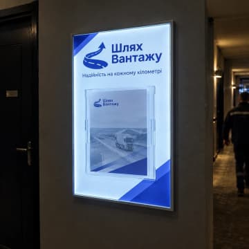 Стенд з підсвіткою і прозорою кишенею на стіні коридору