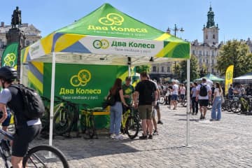 Шатер з друком на міській площі, поруч велосипеди