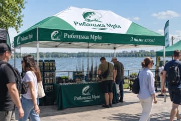 Зелений шатер з друком на набережній, під ним прилавок
