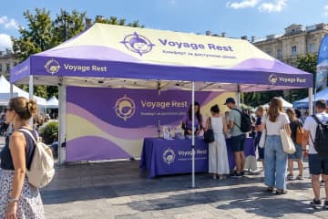 Фіолетовий шатер з друком на вуличній події, під ним стіл з буклетами