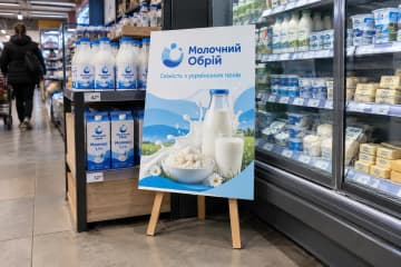 Хардпостер на підставці біля холодильників з молочною продукцією