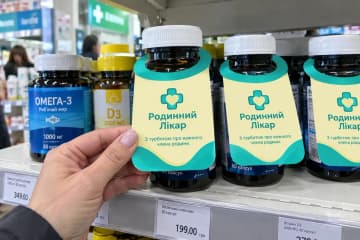 Некхенгер на баночці з вітамінами в руці покупниці в аптеці