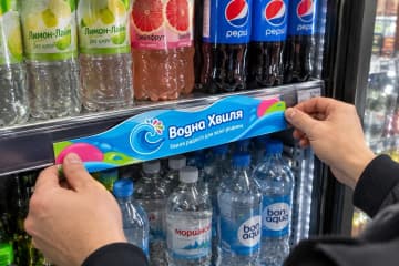 Мерчандайзер кріпить хвилястий шелфтокер на полицю з водою