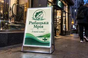 Штендер з підсвіткою ввечері біля входу в магазин риболовлі
