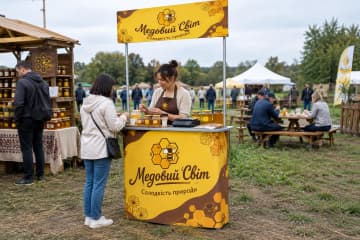 На фото промостіл Classic розміром 85×50 см на ярмарку пасіки поруч із дегустаційним столом.