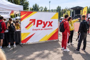 На спортивному фестивалі показано брендвол Chrome розміром 300×200 см: хромований каркас із труб, ніжки на землі та ПВХ-банер, прив’язаний через люверси.