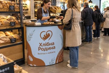 Промостіл Oval розміром 120×55 см у пекарні, де видно овальну стільницю та друковану панель спереду.