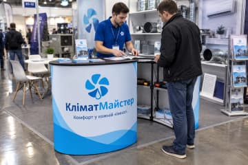 Промостіл Oval розміром 150×50 см на стенді сервісу кліматичної техніки, де видно овальну стільницю та друковану панель спереду.