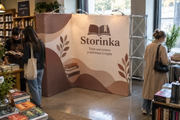 У книгарні біля читального куточка розташовано кутовий поп-ап MultiForm заввишки близько 226 см із тканинним графічним друком для Storinka.