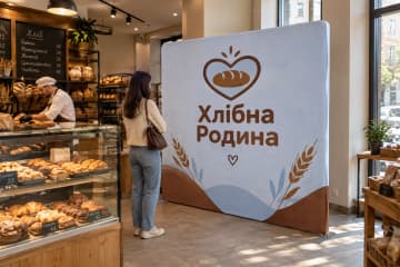 Прямий текстильний поп-ап 250×230 см для бренду «Хлібна Родина» у пекарні біля вітрини з хлібом і випічкою.