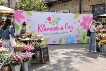 Прямий текстильний поп-ап 610×230 см для бренду «Квітковий Сад» на квітковому ринку біля букетів, столу каси та відвідувачів.