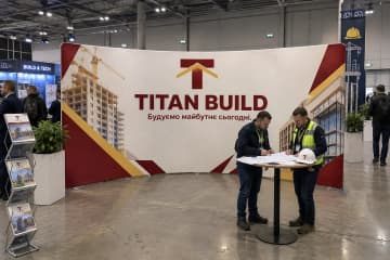 На фото показано текстильний поп-ап 610×230 см на стенді будівельної компанії у виставковій залі.