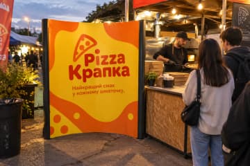 Криволінійна поп-ап стіна Pop-up Arc 135×230 см на вході піцерії на вуличному фуд-фесті з вертикальними друкованими ПВХ-панелями.