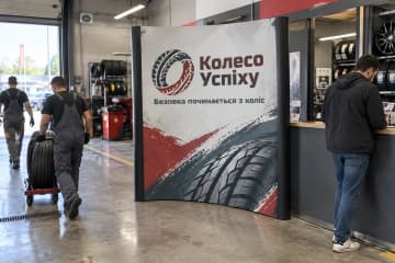 Криволінійна поп-ап стіна Pop-up Arc 200×230 см у сервісній зоні шиномонтажу з вертикальними друкованими ПВХ-панелями.