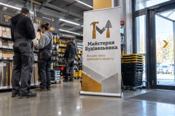 Ролл-ап Royal з округлою краплеподібною основою, розмір 85×200 см, у вході будівельного магазину серед стелажів.