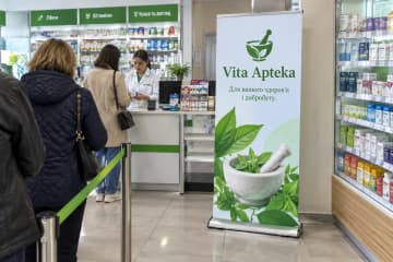 Ролл-ап Royal з округлою краплеподібною основою, розмір 100×200 см, у зоні каси аптеки біля вітрини.