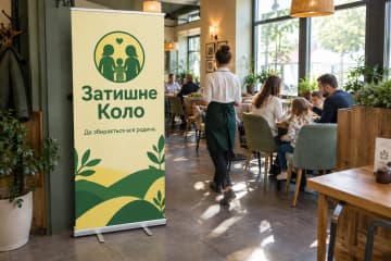 Ролл-ап Classic Plus 100×200 см у сімейному ресторані біля залу зі столами, на фото видно широку алюмінієву касету з хромованими торцями.