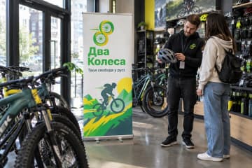 Ролл-ап Classic Plus 80×200 см у веломагазині серед велосипедів, на фото видно широку алюмінієву касету та хромовані торці.