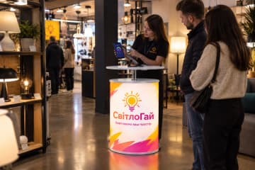 Телескопічний промо-стіл з LED-підсвіткою на алюмінієвому каркасі з друкованим фронтом встановлено в салоні освітлення поруч із вітринами та відвідувачами.