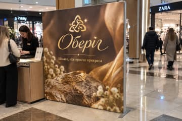 На фото текстильний стенд Тексвол 200×200 см у просторі ювелірного бренду в торговому центрі, поруч є вітрина та консультант.