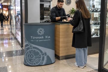 Овальний промостіл Oval Textile розміром 80×53 см у сервісному кіоску з ремонту годинників.