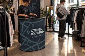 Овальний промостіл Oval Textile розміром 80×53 см у поп-ап магазині одягу.