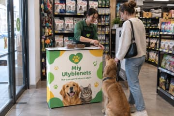 На фото промостіл Textile розміром 103×40 см у зоомагазині біля входу та полиць із товарами.