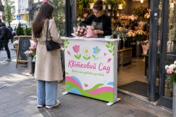 На фото промостіл Textile розміром 100×35 см біля входу до квіткового магазину.