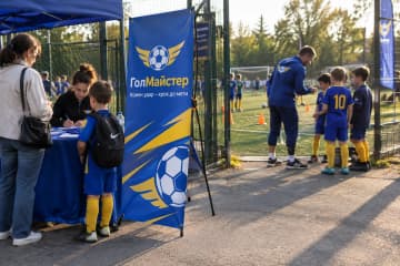 Х-банер Junior 80×180 см для футбольної школи ГолМайстер біля реєстраційного столу на полі.