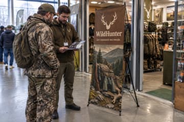 На профільному мисливському ярмарку біля магазину стоїть Х-банер Royal 60×160 см на Х-подібному каркасі з натягнутим друкованим банером.