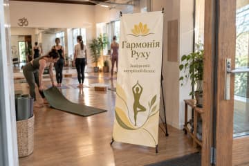 У залі йога-студії біля входу стоїть Х-банер Royal 60×160 см із друкованим банером на Х-подібному каркасі.