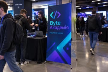 Х-банер Prime 120×200 см на айті-конференції біля реєстрації та столу з ноутбуком.
