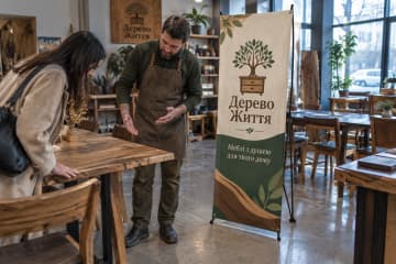 Х-банер Classic 60×160 см у майстерні меблів поруч із дерев’яними столами та стільцями.