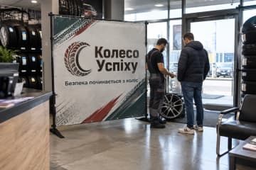 Брендвол Cross 300×200 см стоїть у салоні шиномонтажного магазину Колесо Успіху біля входу та стелажів із шинами, а конструкція на Х-подібних хрестовинах помітна повністю.