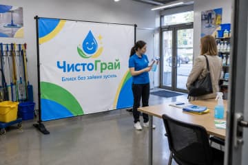 Брендвол Cross 300×200 см стоїть у навчальній кімнаті сервісу ЧистоГрай поруч із прибиральним інвентарем і столом, а стійки на Х-подібних опорах видно на підлозі.