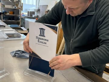 Майстер вставляє вкладиш в акриловий менюхолдер