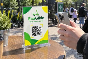 Менюхолдер з QR-кодом на столику вуличного кафе, код сканують телефоном