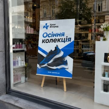 Хардпостер на дерев'яній підставці у вітрині магазину взуття