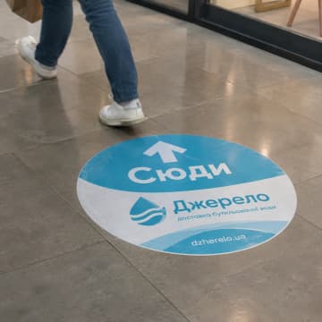 Круглий підлоговий стікер зі стрілкою на плитці в торговому центрі