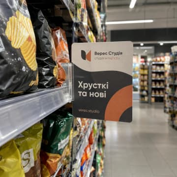 Прямокутний стопер на прозорому кріпленні на полиці зі снеками