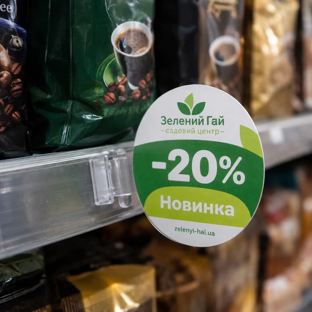 Круглий воблер зі знижкою на прозорій ніжці біля полиці з кавою